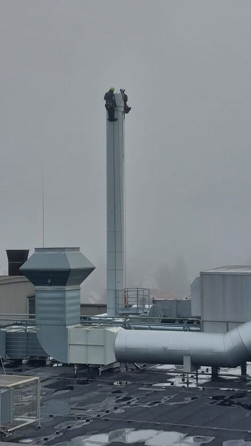 Industriekletterer an einem Industriekamin installieren einen Fangmast und eine HVI-Blitzableitung in Mannheim.